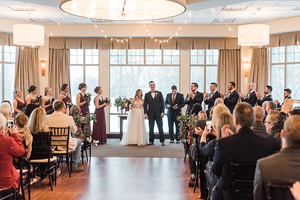 Wedding party and bride and groom during indoor winter ceremony at Scioto Reserve Country Club in Powell, Ohio