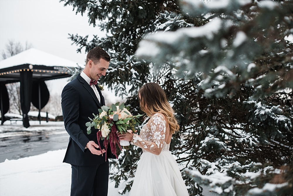 The bride and groom share their first look in the snow outside on their wedding day