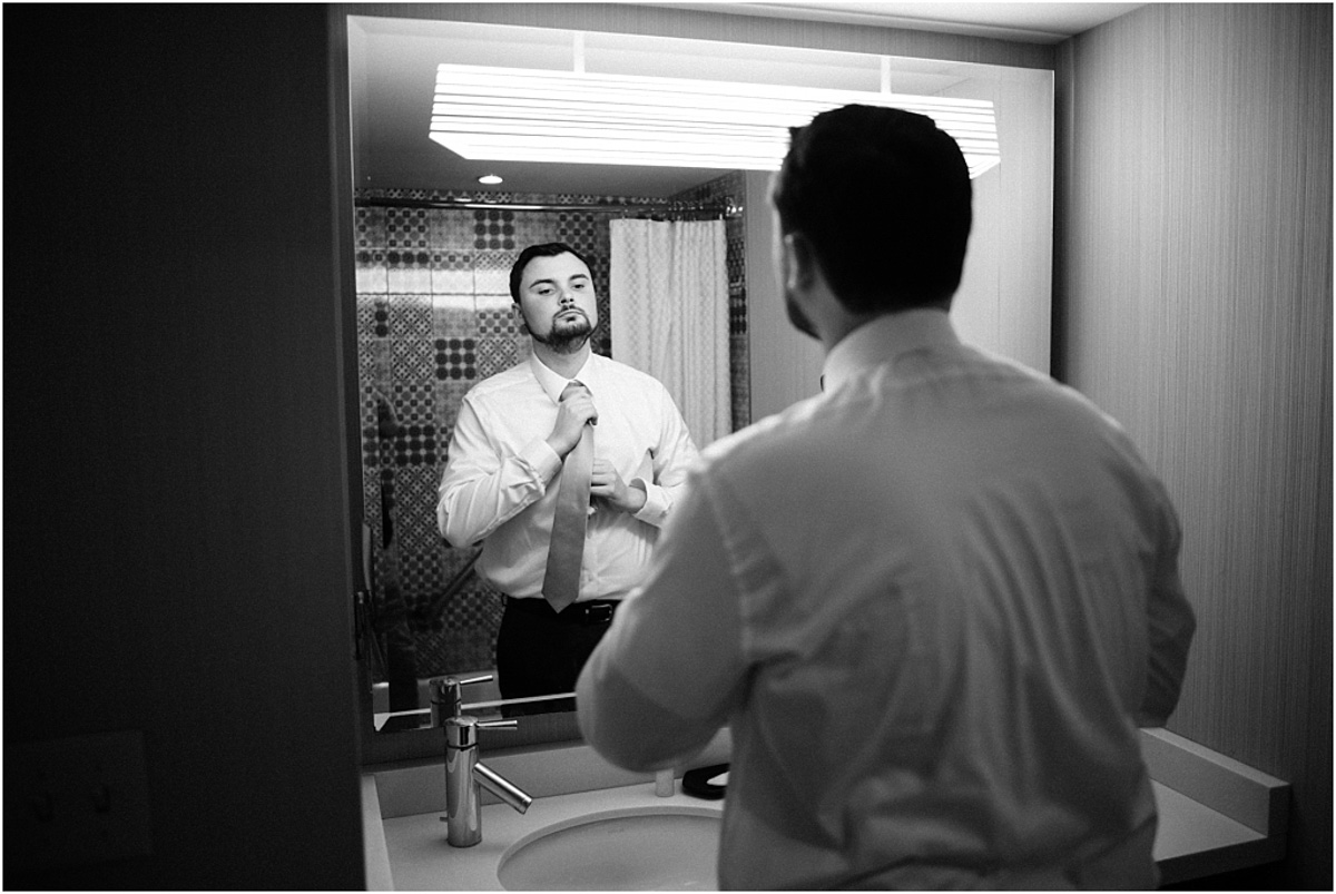 groom tying his tie in mirror