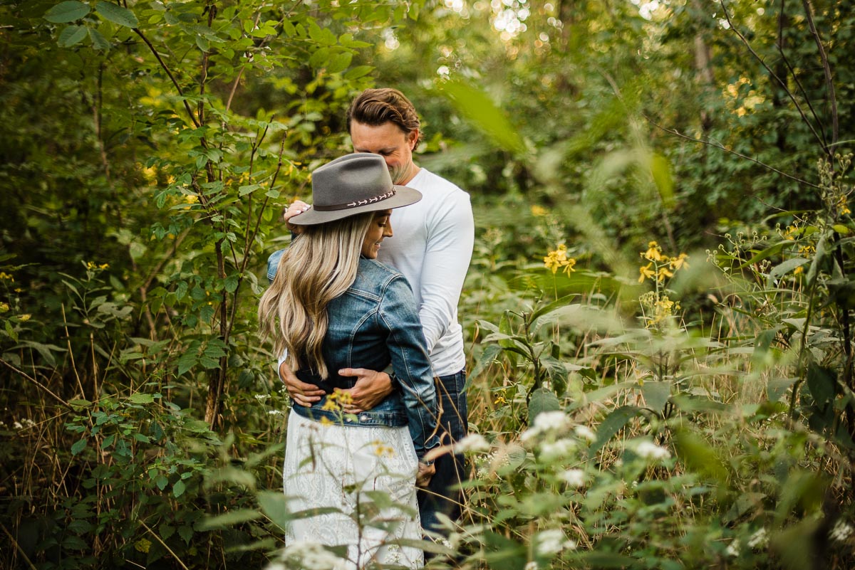 couple snuggling in field for engagement session