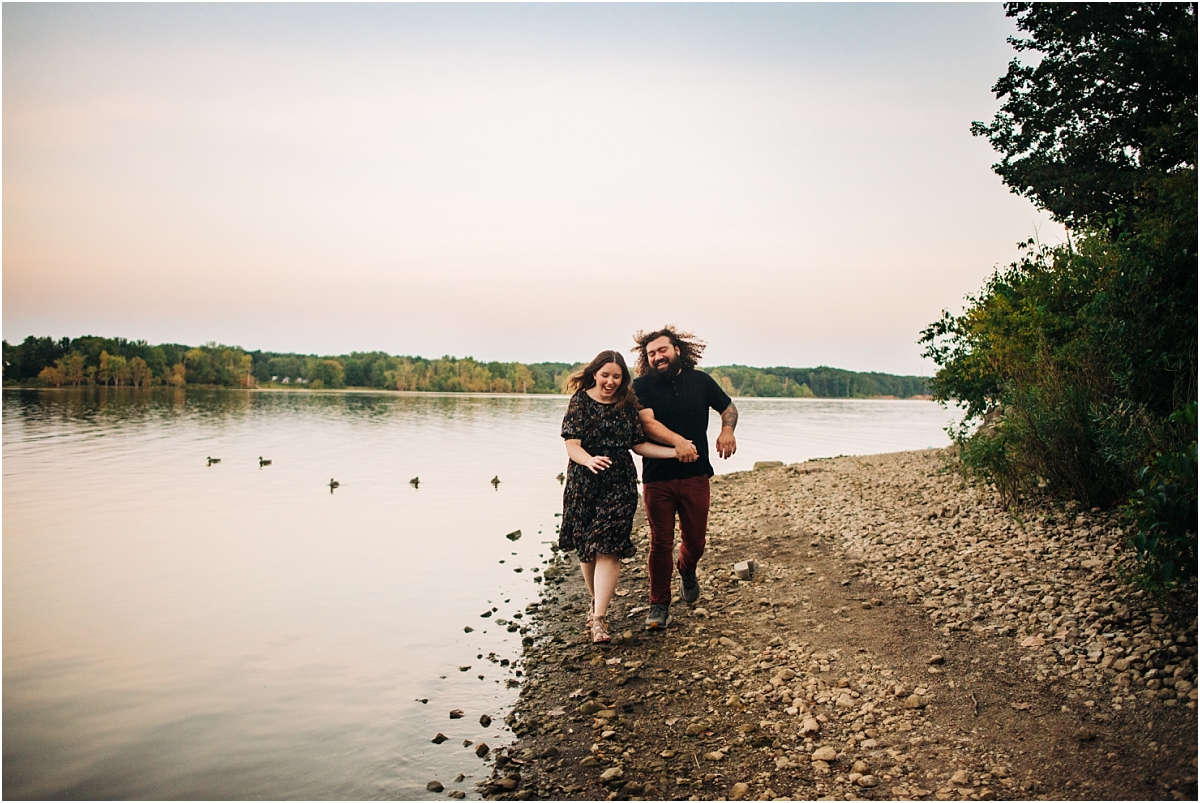 couple running along shore line in columbus ohio for their engagement pictures