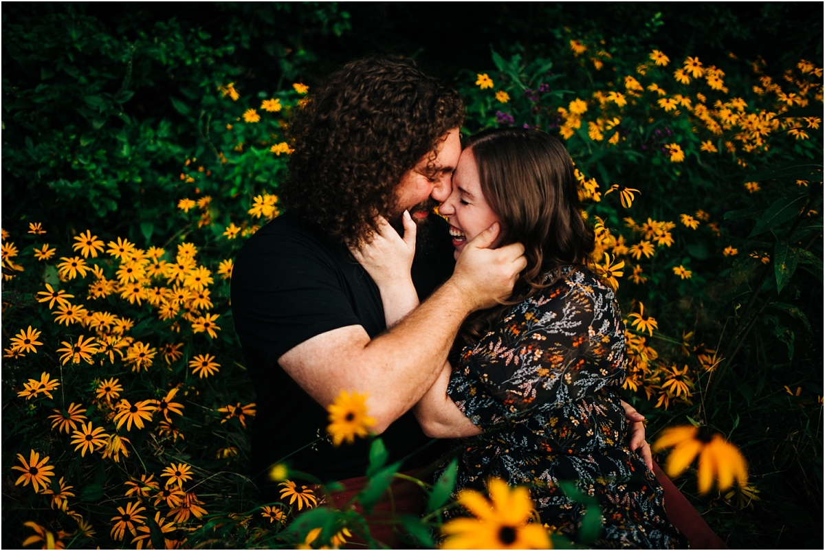 couple snuggling for their engagement photos in a wildflower field