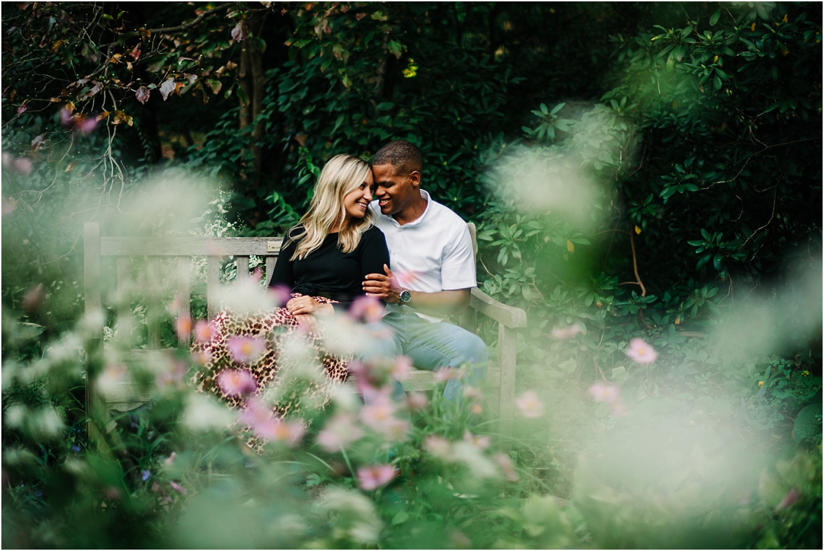 couple sits on bench surrounded by flowers