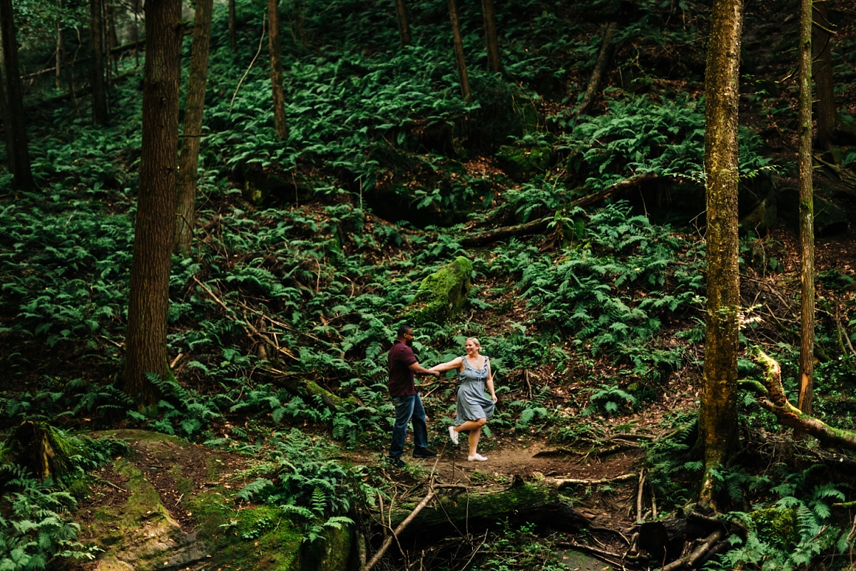 A couple playfully looking at each other while they walk through the forest at Old Man's Cave