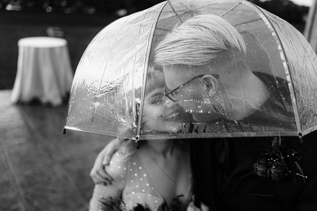 water droplets on umbrella with bride and groom underneath