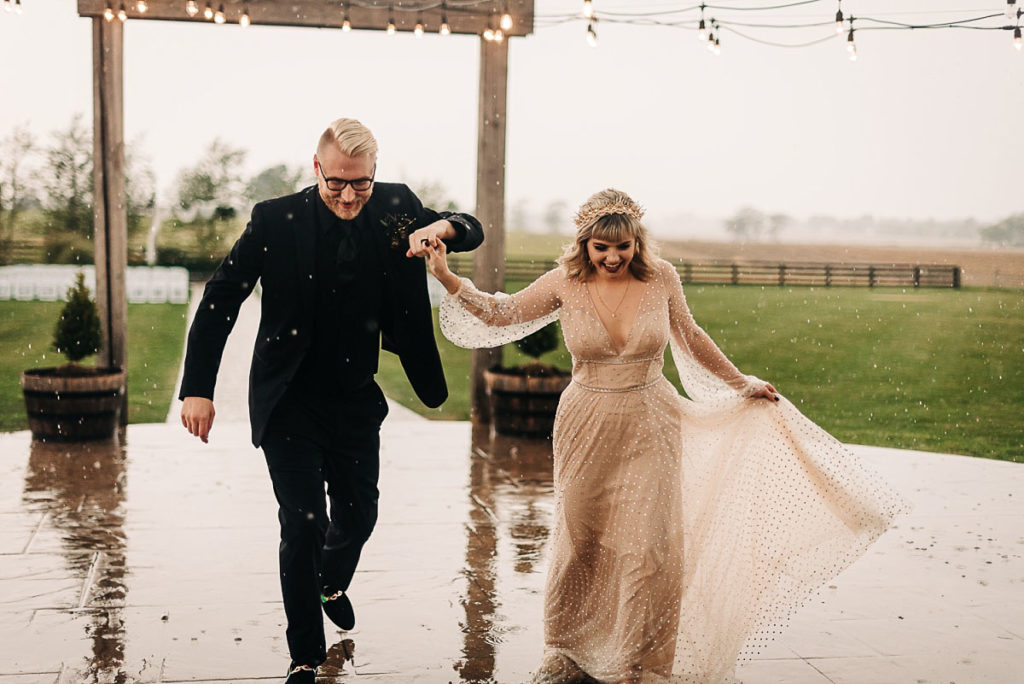 bride and groom running after rain starts falling