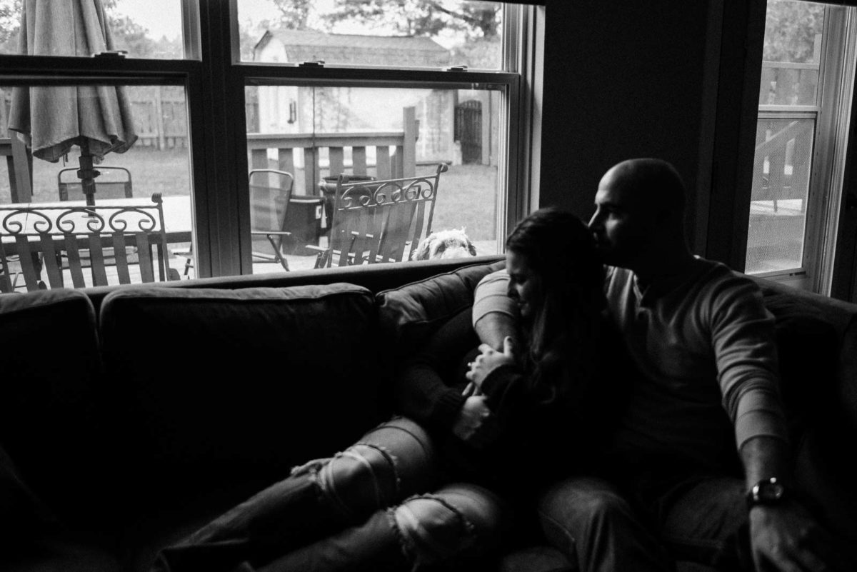 black and white photo of engaged couple snuggling on couch