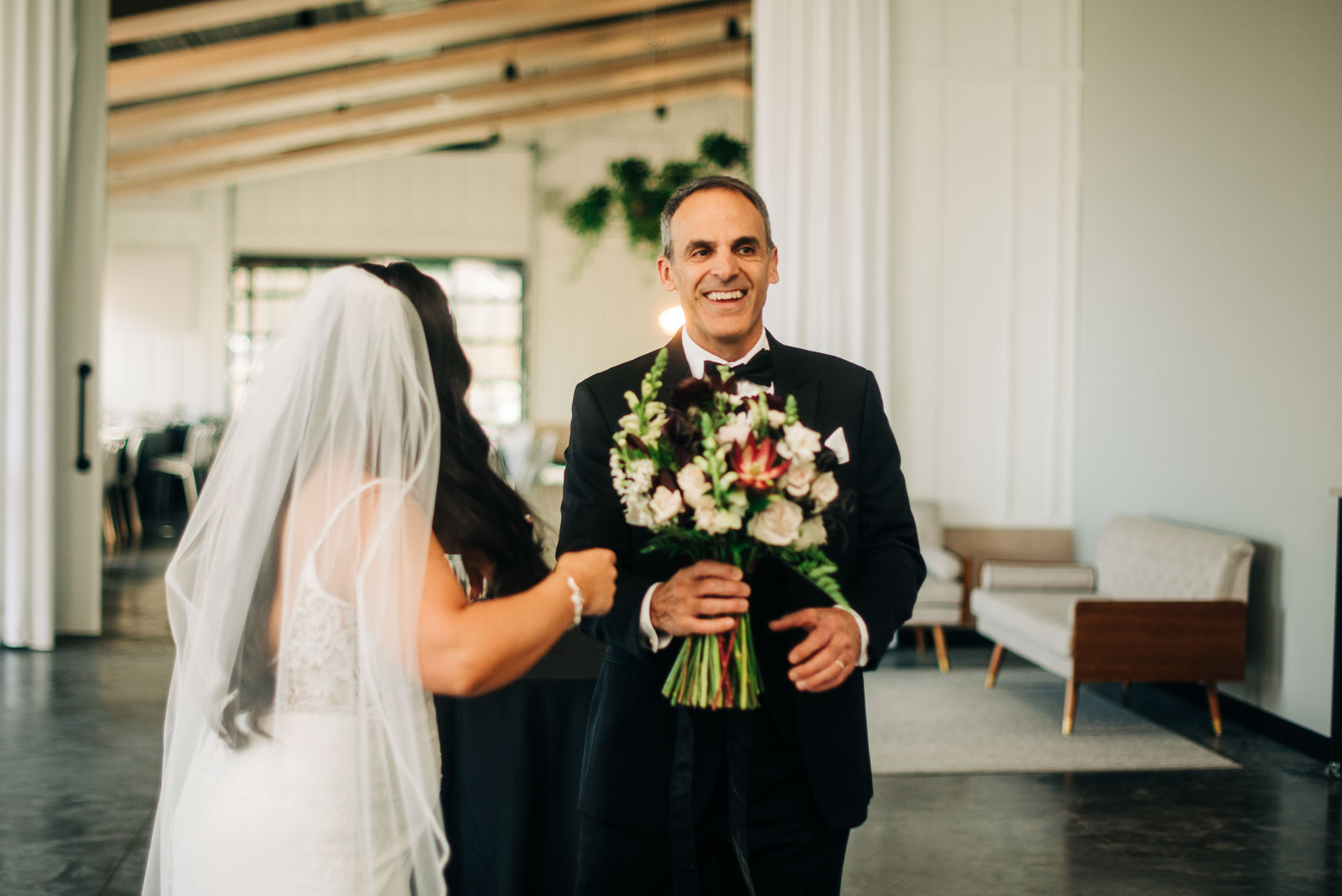 father of the bride holding the brides bouquet