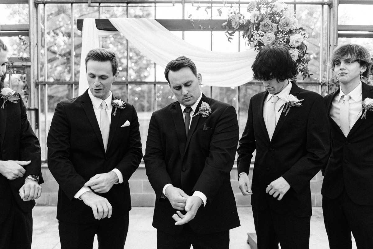 groom and groomsmen fix their suits after the wedding ceremony is over