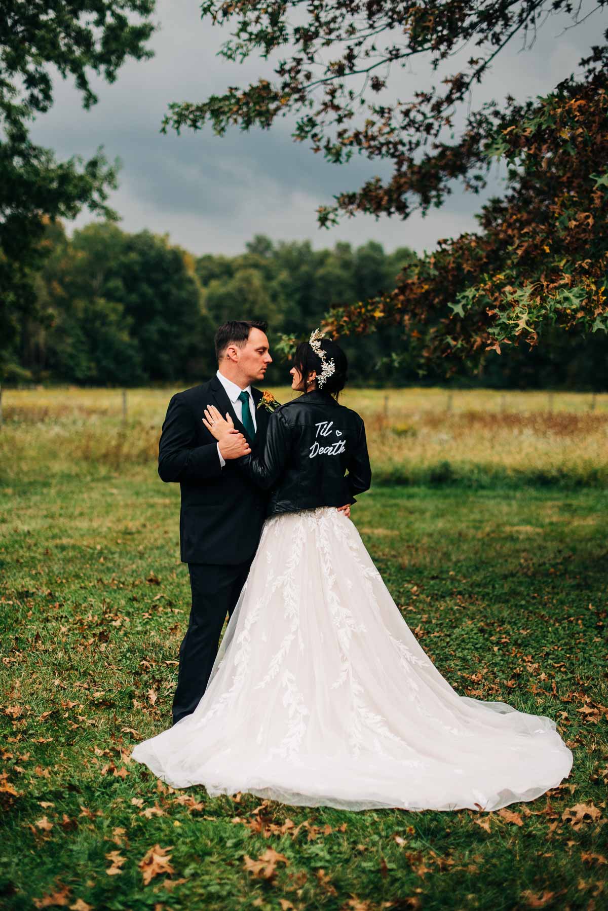 Bride and groom pose for portraits with fall foliage in the background
