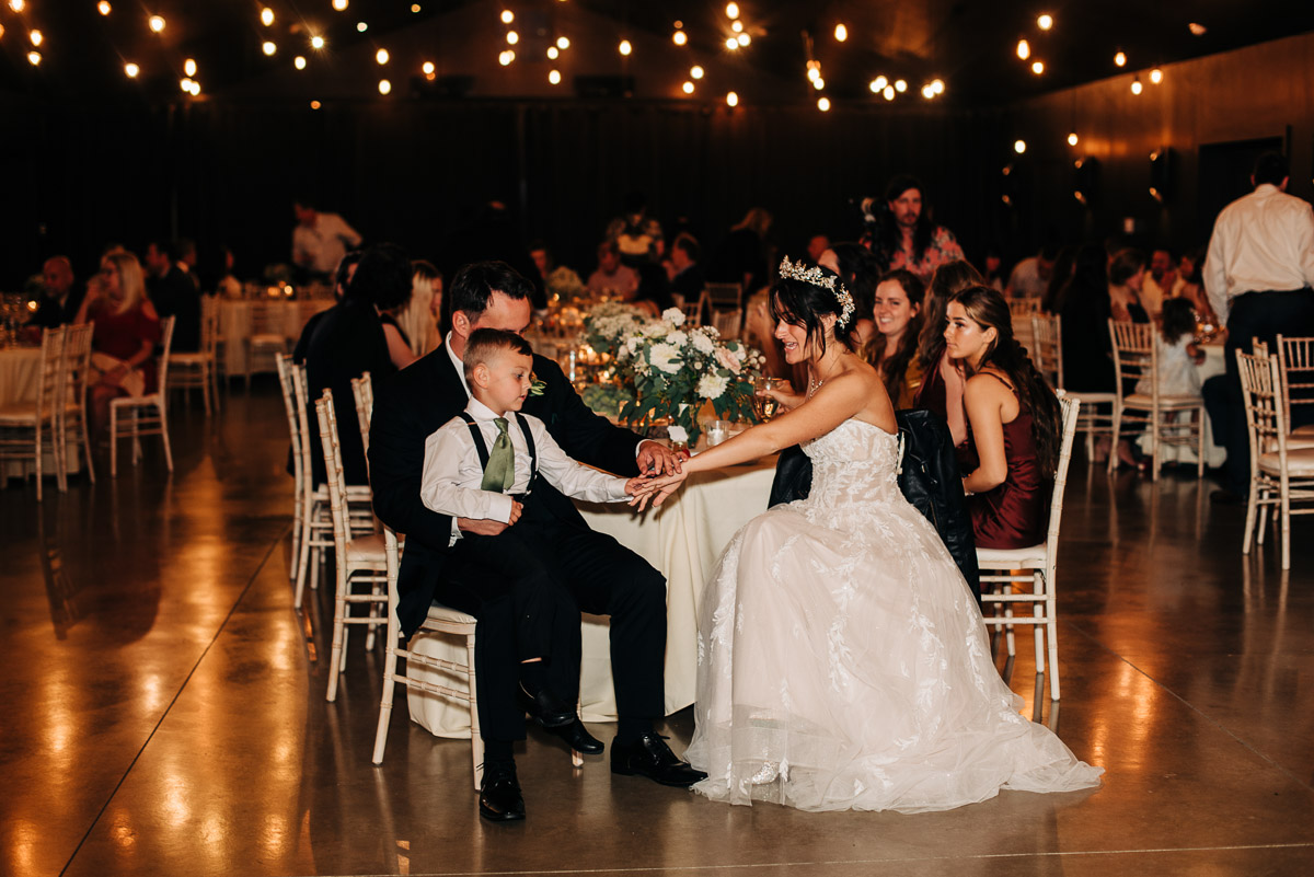 Bride shows her step son her ring during their reception at Oak Grove