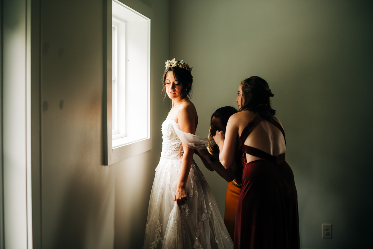 Dramatic lighting on the bride while she gets her wedding dress on