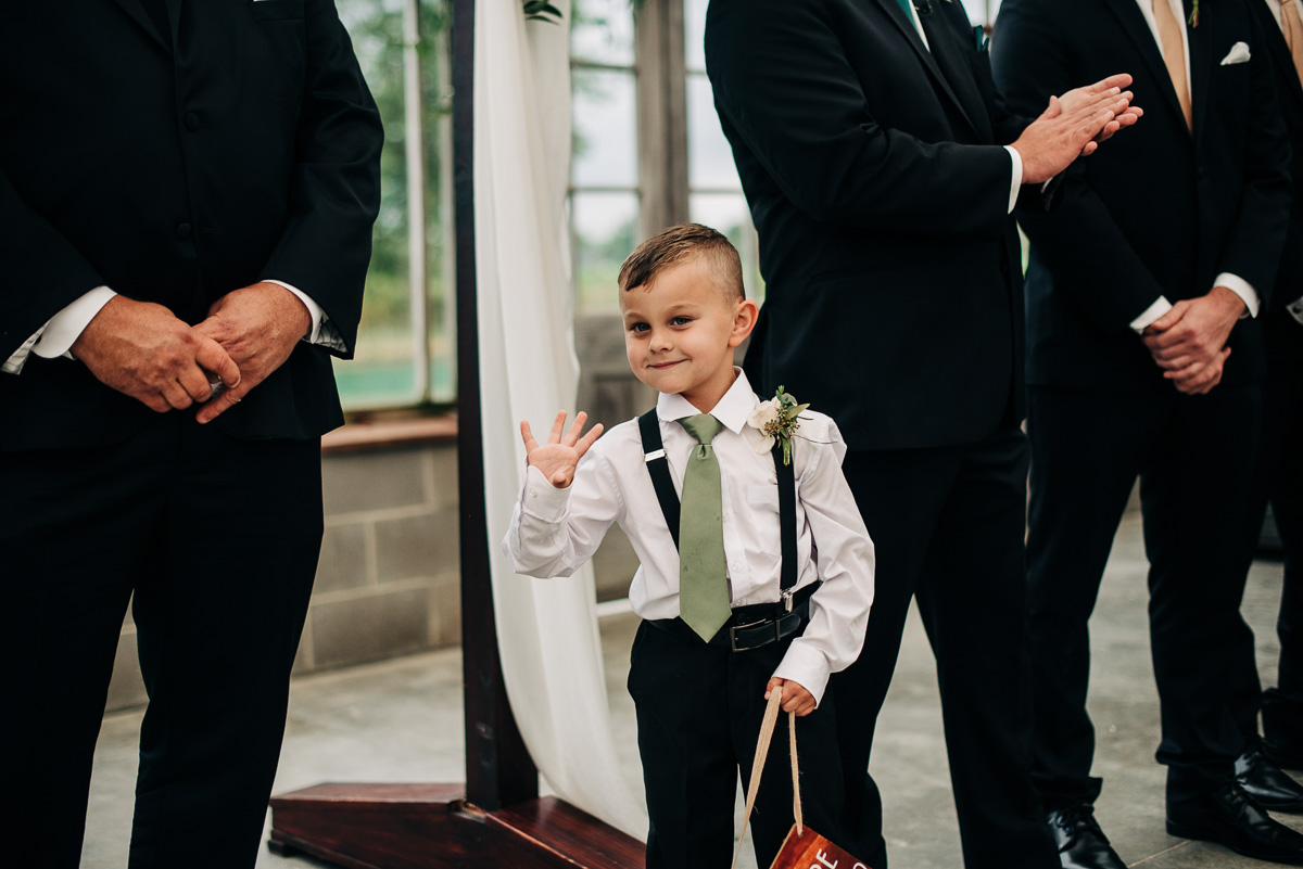 Ring bearer waves to guests while waiting for the bride at the Oak Grove greenhouse