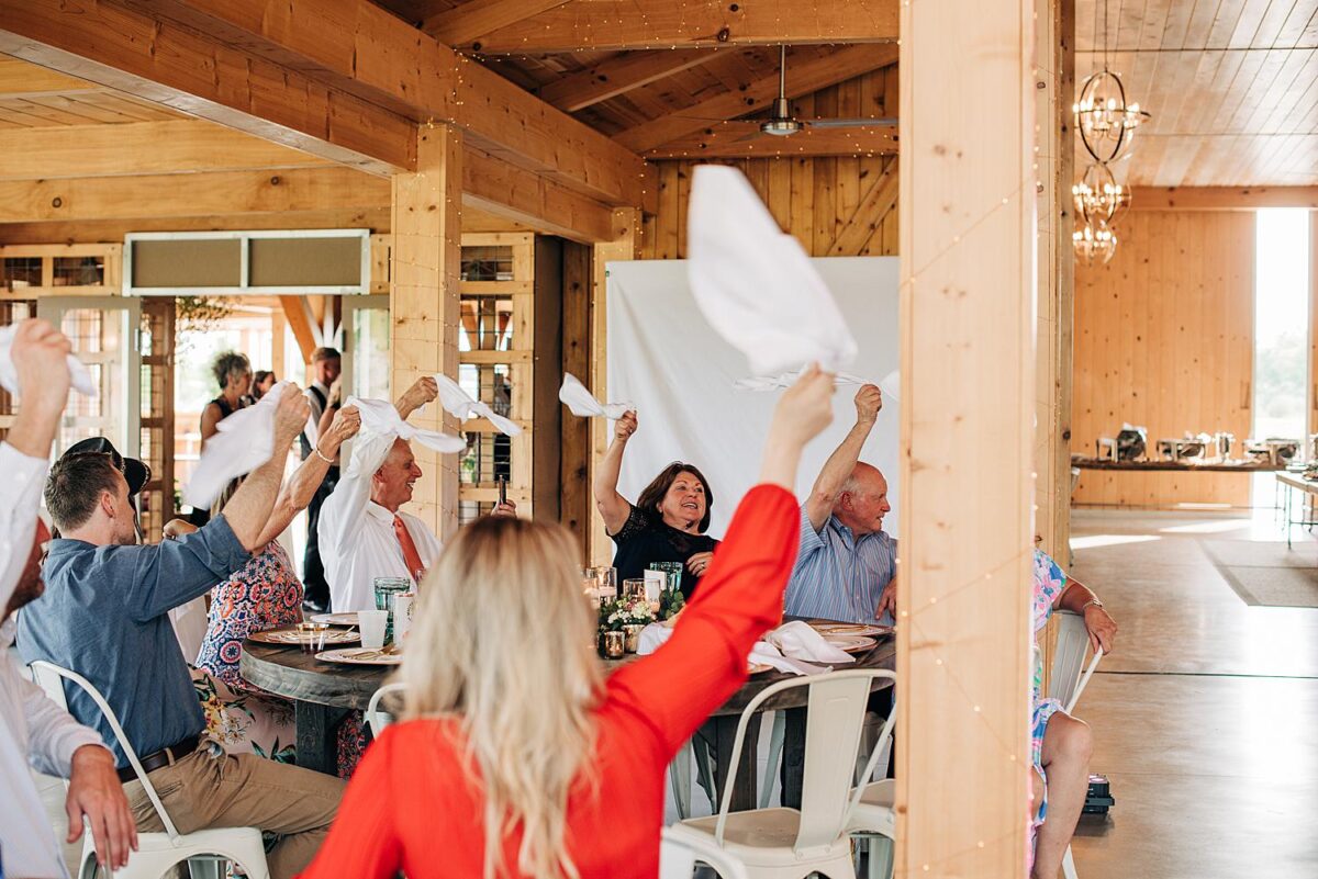 Guests wave their napkins in the air as they wait for the wedding party to make their grand entrance
