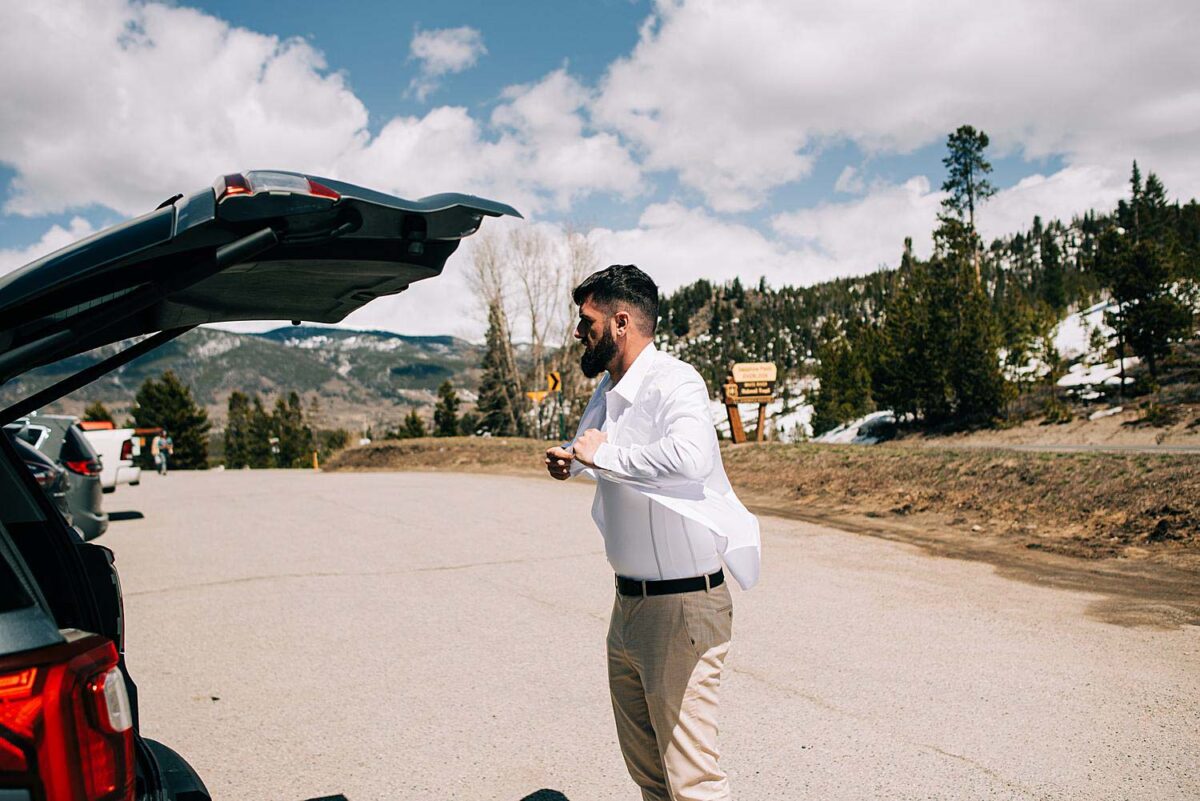 Groom getting dressed in the parking lot of Sapphire Point Overlook in Dillon, Colorado