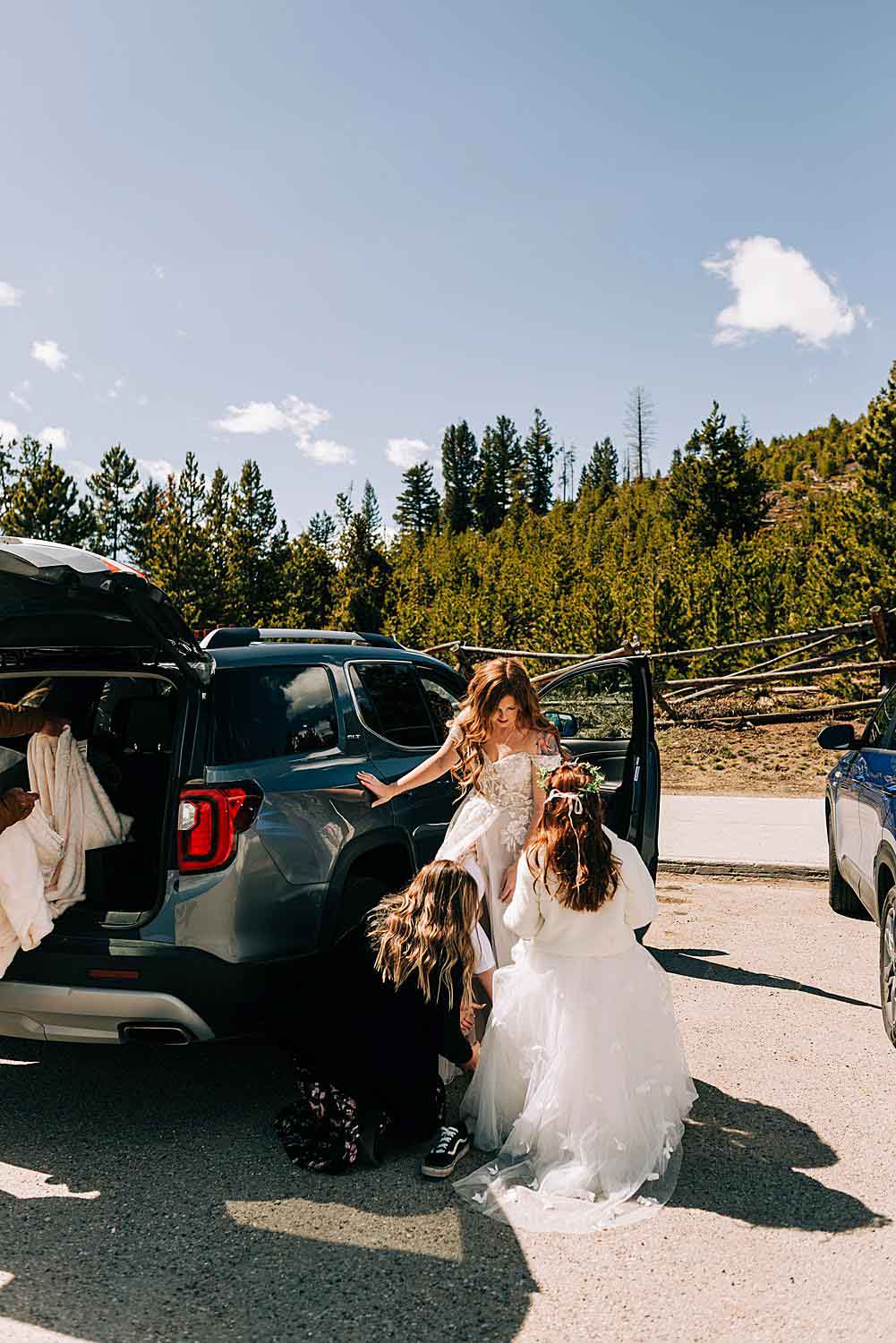 Bride gets help putting her dress on in the parking lot for her Sapphire Point Overlook Elopement