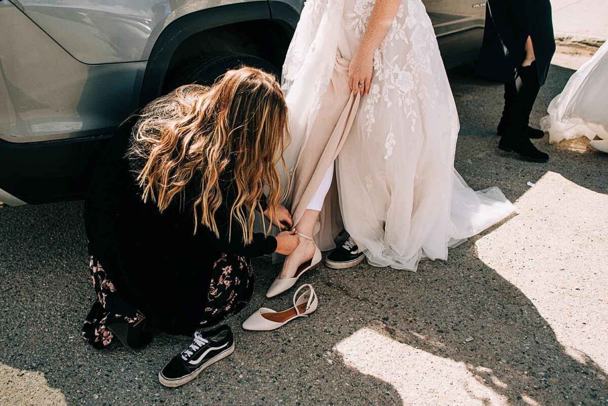 Bride gets help putting her dress on in the parking lot for her Sapphire Point Overlook Elopement